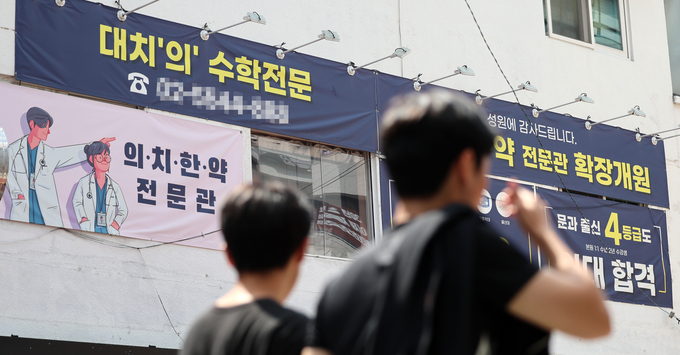 2025학년도 대입 수시 원서접수를 하루 앞둔 8일 서울 강남구 대치동 학원가의 의대 입시 관련 학원 앞을 한 시민이 지나가고 있다. 사진=뉴시스